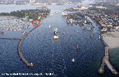 Picture: Harbour approch channel (centre) with Rostock port (background), "Yachthafenresidenz Hohe Düne" (left) and Warnemünde lighthouse (right).